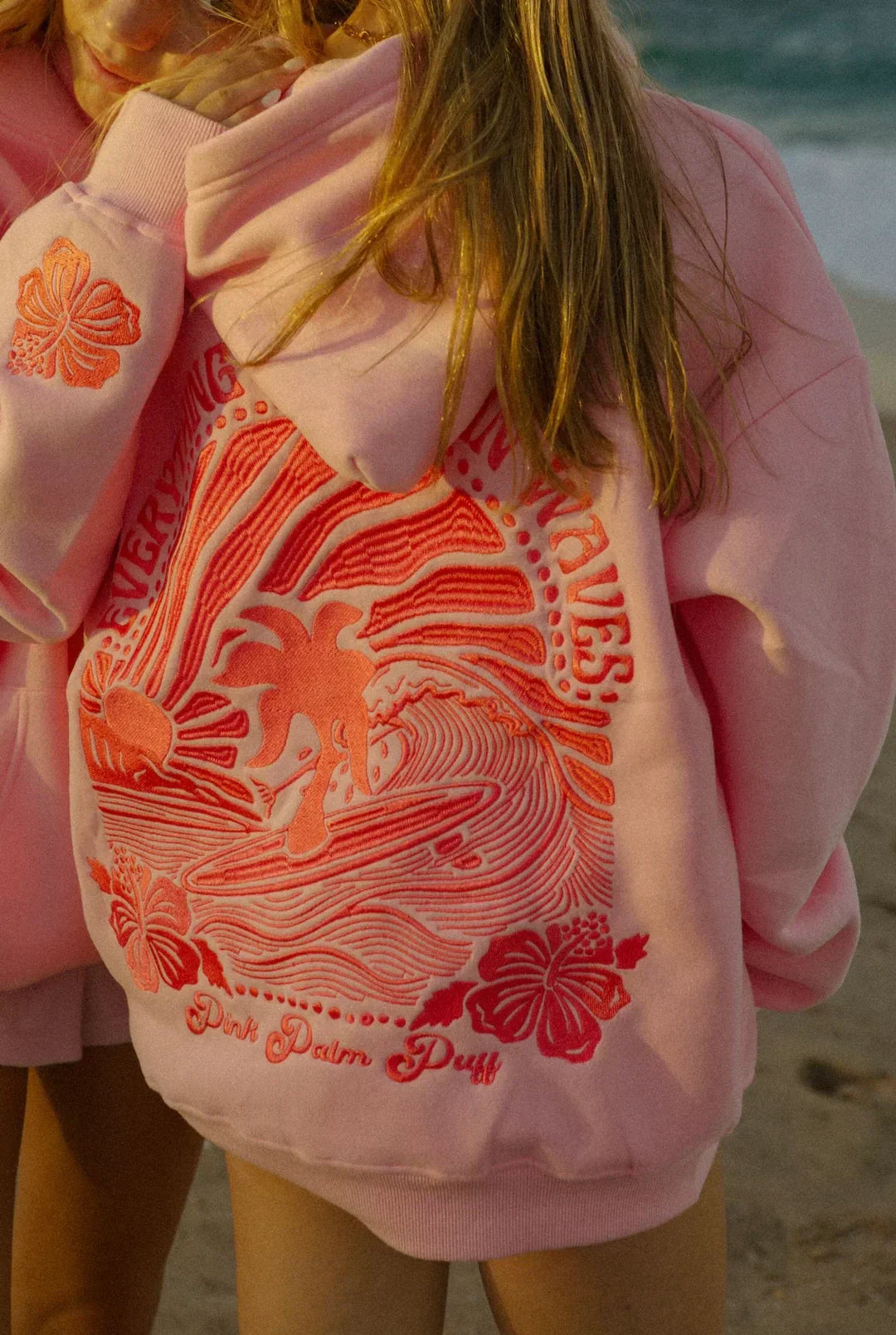 Blauwe hoodie met tropische print gedragen bij een palmboom.