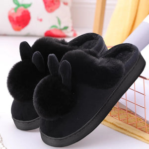 Fuzzy indoor slippers with playful pompom details.
